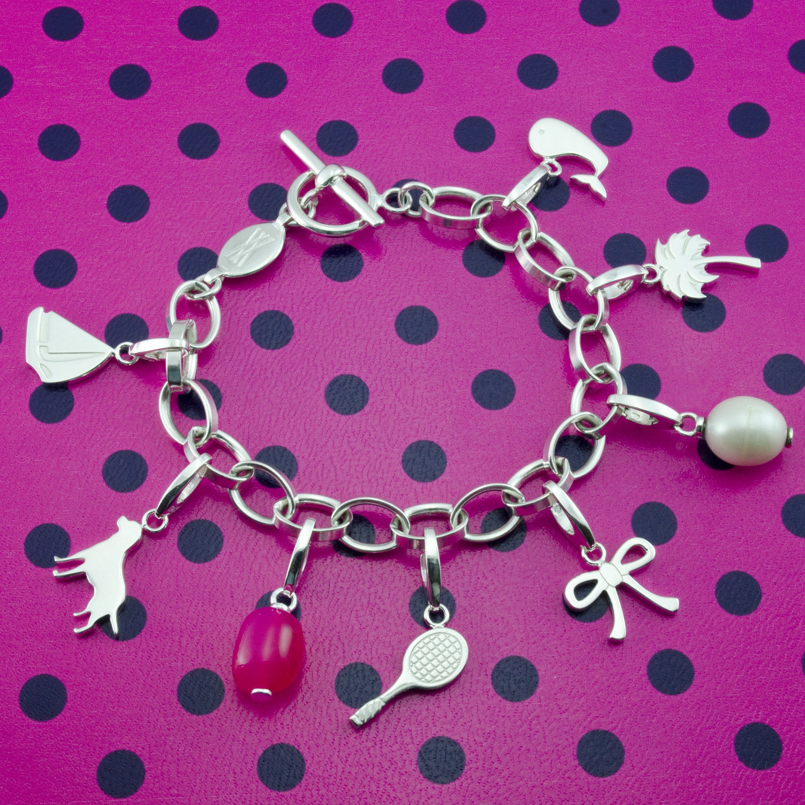 Sterling Silver Charm Bracelet with sailboat charm, dog charm, pink chalcedony charm, tennis racket charm, bow charm, pearl gemstone charm, palm tree charm and whale charm