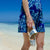 Woman walking on beach wearing sterling silver charm bracelet and holding Jack Rogers Hamptons Sandals