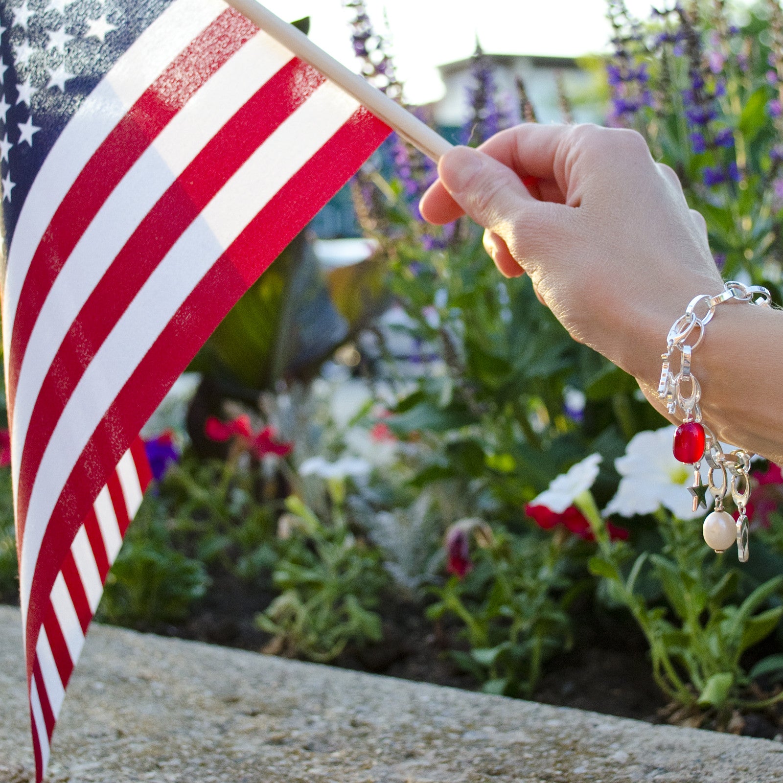 Woman wearing sterling silver charm bracelet holding American flag